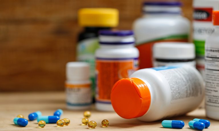 Assorted supplement capsules and bottles displayed on a wooden surface, representing OEM medicine and halal certified healthcare products available in Singapore.
